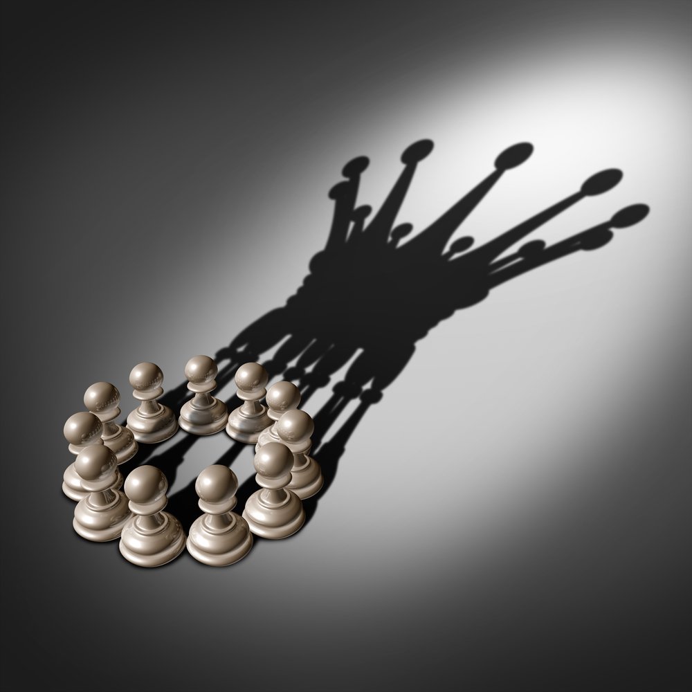 Leadership Team Are You a Humble Leader? - Leadership team and business group concept as an organized company of chess pawn pieces joining forces and working together united and as one in agreement to cast a shadow shaped as the crown of a king.