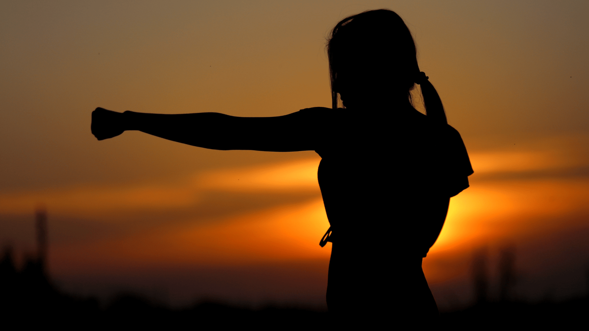 Building Resilience - person silhouetted against a sunrise or sunset, performing a punching motion